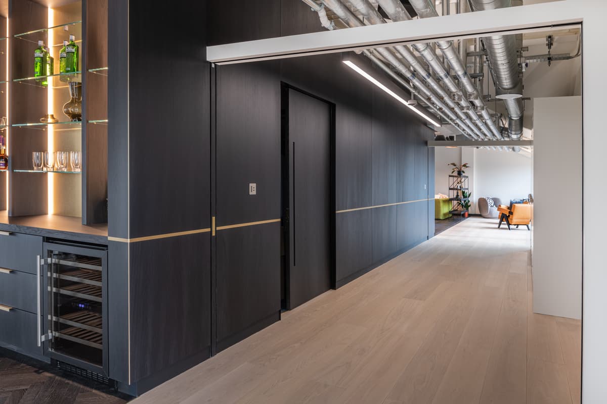 A contemporary office interior from kitchen area down to seating area with a fully open pocket sliding door.